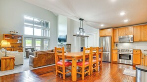 A spacious kitchen with wooden cabinets, stainless steel appliances, and a dining area with a wooden table and chairs. - Ski-In/Ski-Out Granby Penthouse w/ Mountain Views! (Granby)