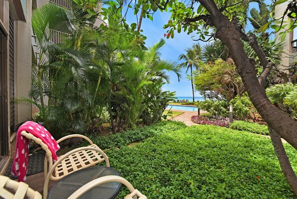 A lush garden with a pool and a view of the ocean.