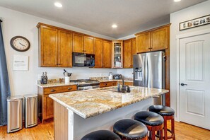 A kitchen with wooden cabinets, stainless steel appliances, a granite countertop, and a clock on the wall. - Granby Home w/ Hot Tub + Ski, Golf & Pool Access (Granby)