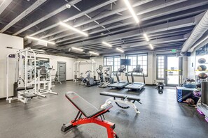 Une salle de sport équipée de divers appareils d’exercice, notamment un banc de développé couché, des tapis de course et un porte-poids.