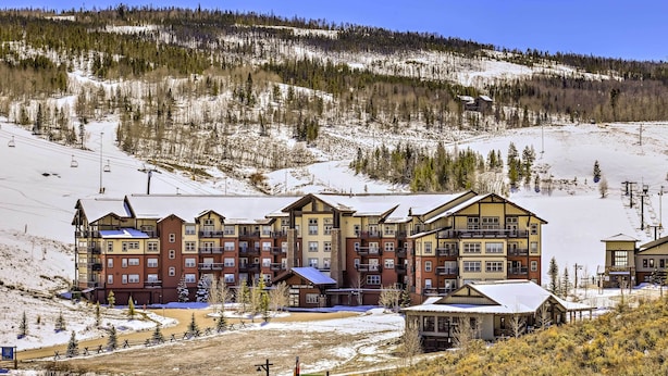A multi-story hotel with a ski lift in the background, surrounded by snow-covered terrain and trees. - Ski-In/Ski-Out Access: Mtn-View Granby Condo! (Granby)