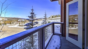 A balcony with a view of a snowy landscape, including trees and distant buildings. - Ski-In/Ski-Out Access: Mtn-View Granby Condo! (Granby)