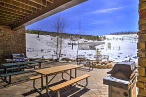 Eine Terrassenanlage im Freien mit Picknicktischen, einem Grill und Blick auf eine verschneite Berglandschaft.
