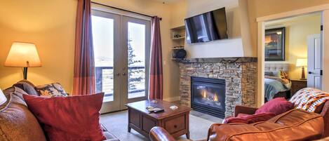 A living room with a fireplace, leather sofa, and a television mounted on the wall.