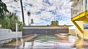 Una piscina con bordo piastrellato, circondata da un solarium in cemento e un muro bianco.