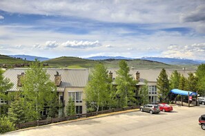 A hotel with a parking lot, a blue canopy, and a view of mountains. - Ski, Soak & Explore! Granby Getaway w/ Mtn Views (Granby)