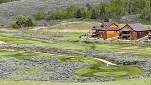 En stor, tvåvåningsbyggnad med en framträdande balkong, belägen på en golfbana med välskötta fairways och greener.