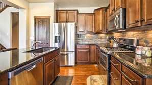 A modern kitchen with wooden cabinets, stainless steel appliances, and a granite countertop. - Patio, Fire Pit, & Ski Mountain View: Granby Home (Granby)