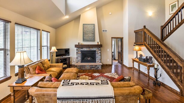 A spacious living room with a fireplace, comfortable seating, and a wooden staircase. - Patio, Fire Pit, & Ski Mountain View: Granby Home (Granby)