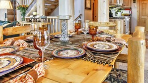 Une table de salle à manger en bois, mise avec des assiettes, des verres et un centre de table.