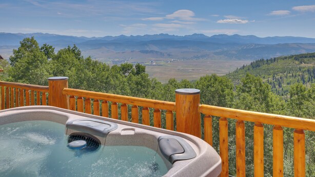 Un bain à remous avec une terrasse en bois et une vue imprenable sur les montagnes.