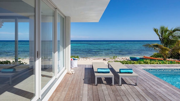 Una terrazza esterna moderna con piscina, poltrona prendisole e vista sull'oceano.