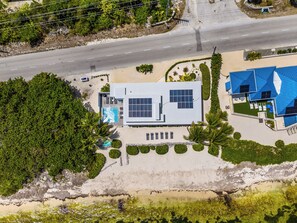 Ein modernes Haus mit Swimmingpool, Solaranlage und Blick auf den Strand.