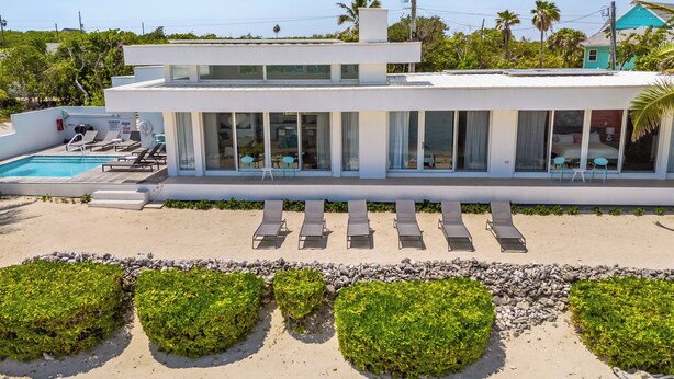 Un hôtel moderne doté d’une piscine, de chaises longues et offrant une vue sur l’océan.