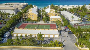 Ein Hotel mit Tennisplatz, Parkplatz und Meerblick.