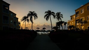 Ein von Palmen gesäumter Weg, der zu einem Strand führt, mit Gebäuden mit Balkonen an den Seiten.