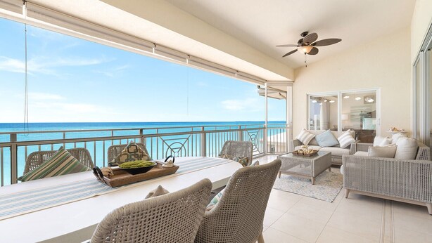 A balcony with a dining table, wicker chairs, and a sofa. - Laguna Del Mar 24 -  3rd floor luxury condo on 7MB - Call Cayman Villas! (Seven Mile Beach)