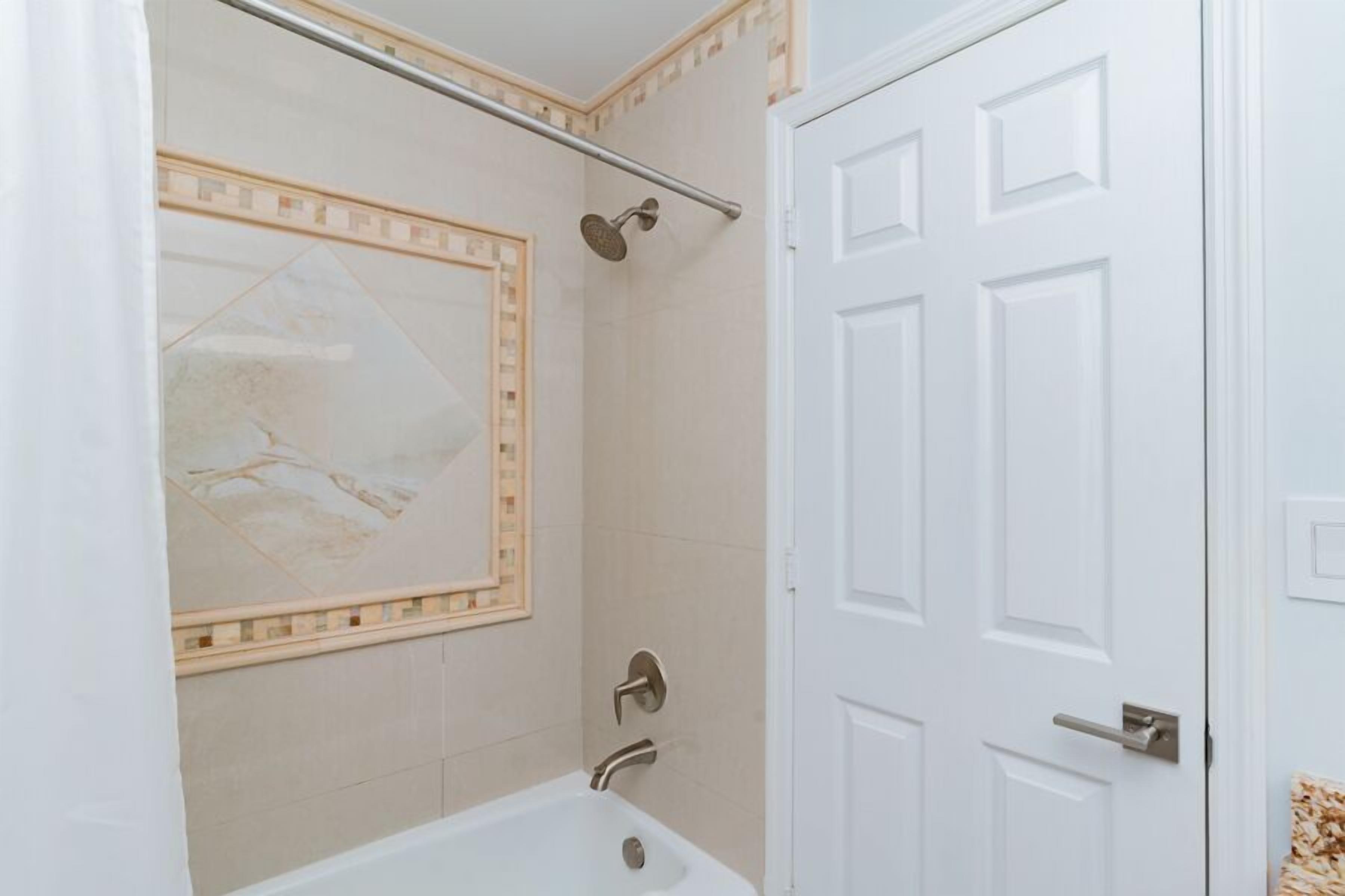 Une salle de bain avec une baignoire, une douche et une porte.
