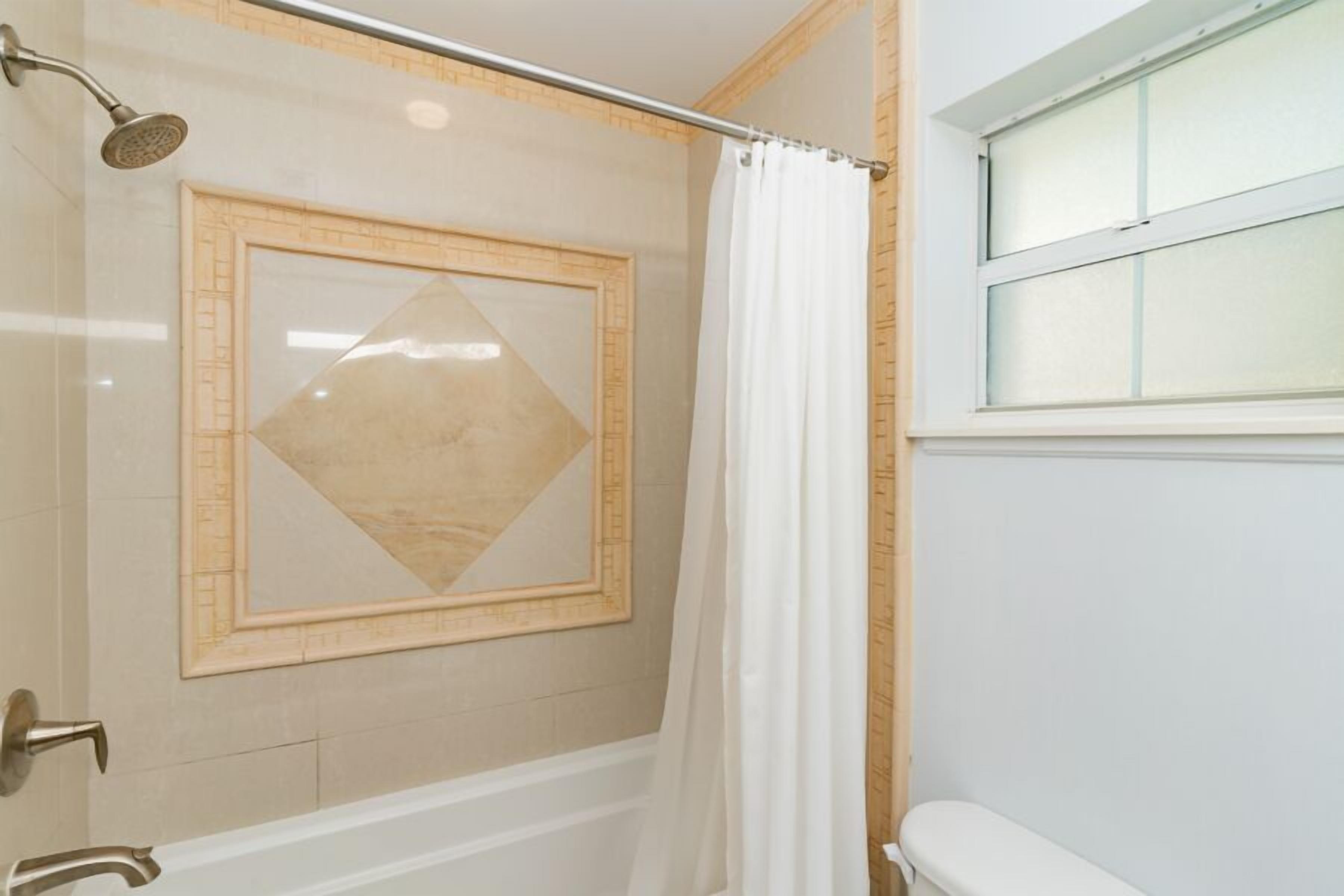 Une salle de bain avec une douche, une baignoire et une fenêtre.
