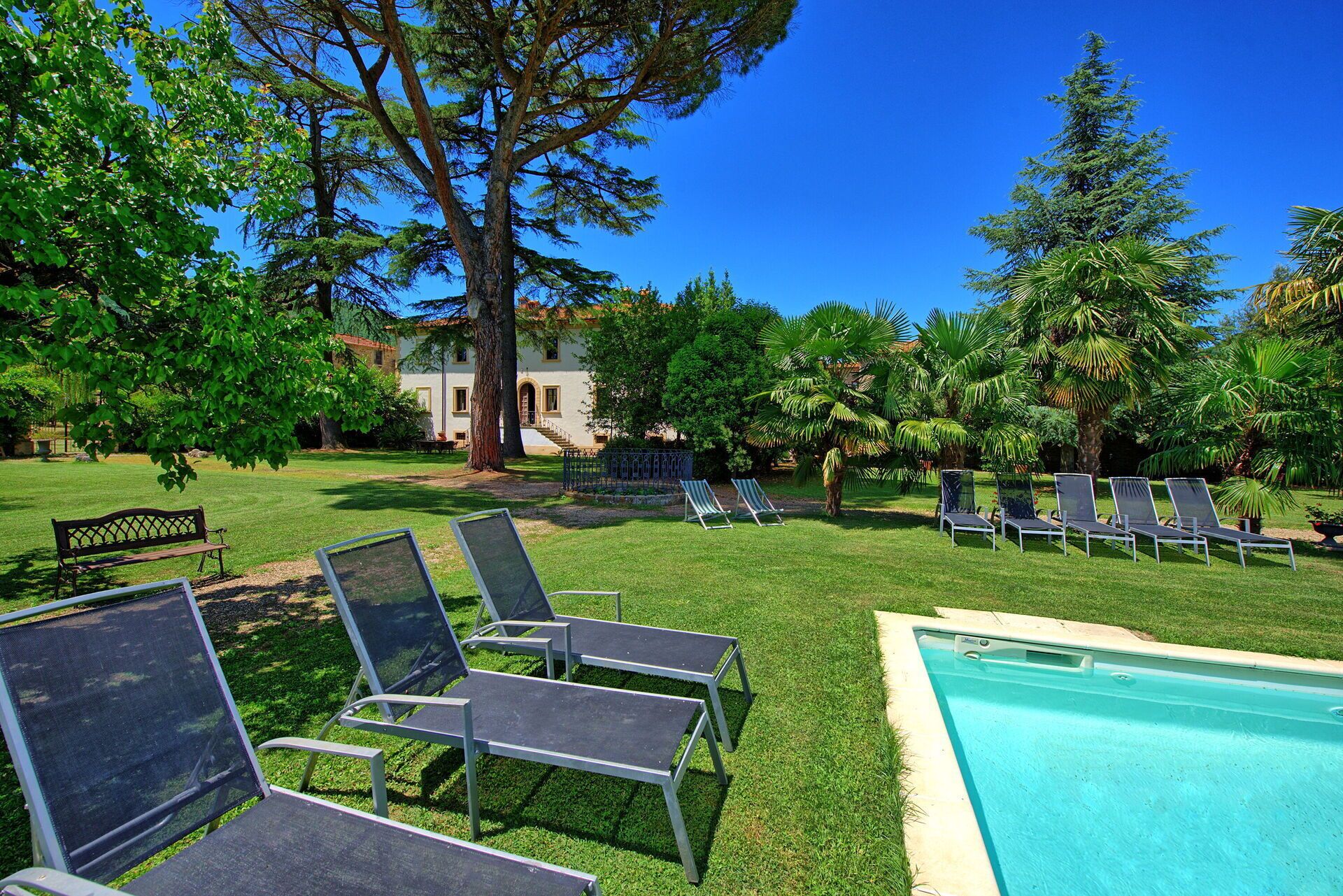 A poolside area with lounge chairs, a bench, and a building in the background.