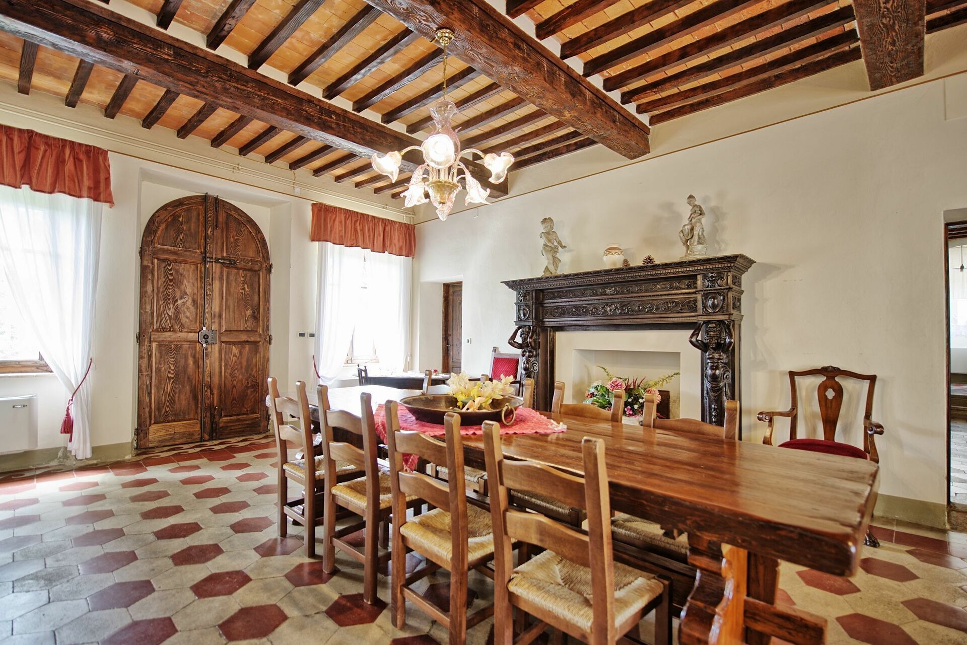 A dining room with a wooden table and chairs, a fireplace, and a large wooden door.