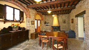 A rustic interior with a stone fireplace, wooden furniture, and a brick archway. - Villa Capolona - Villa Rental with swimming pool in Casentino Valley, Tuscany (Subbiano)