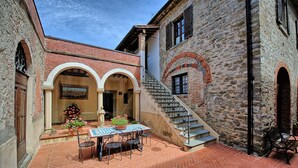 A courtyard with a tiled floor, a table with chairs, and a statue. There is a staircase leading to an upper level. - Villa Capolona - Villa Rental with swimming pool in Casentino Valley, Tuscany (Subbiano)