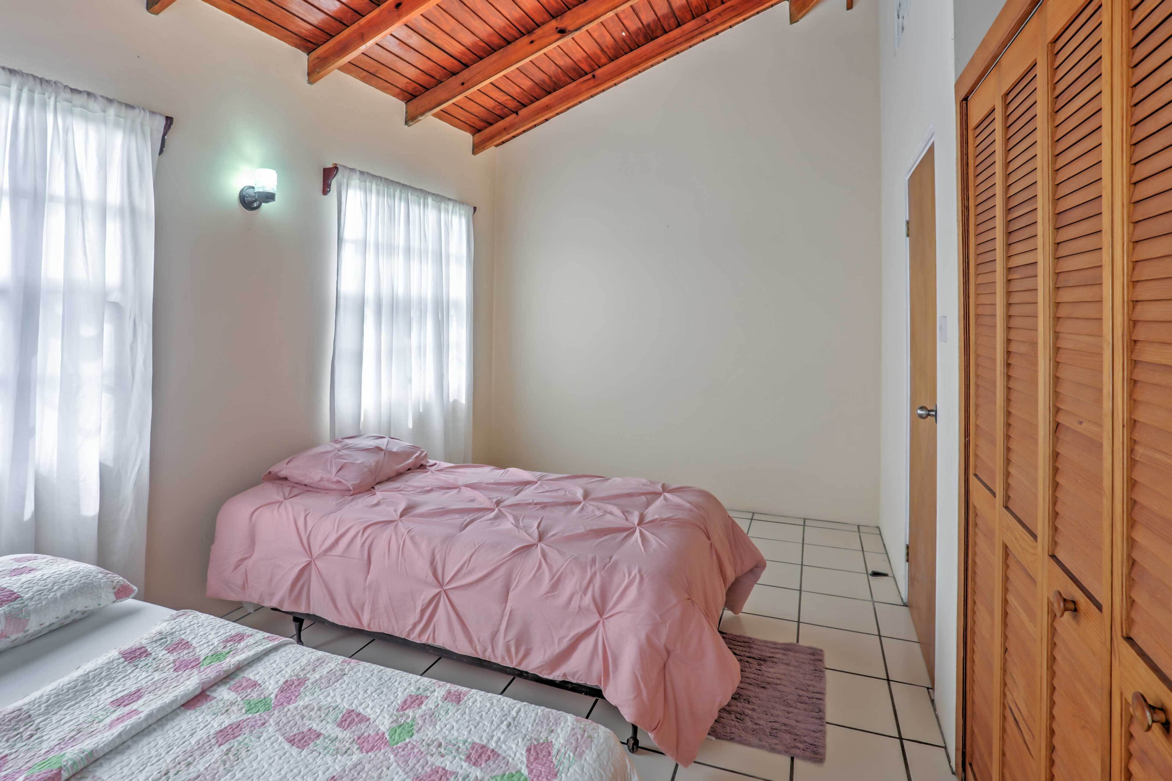 A bedroom with a bed, a bedside table, a wardrobe, and a window with curtains.