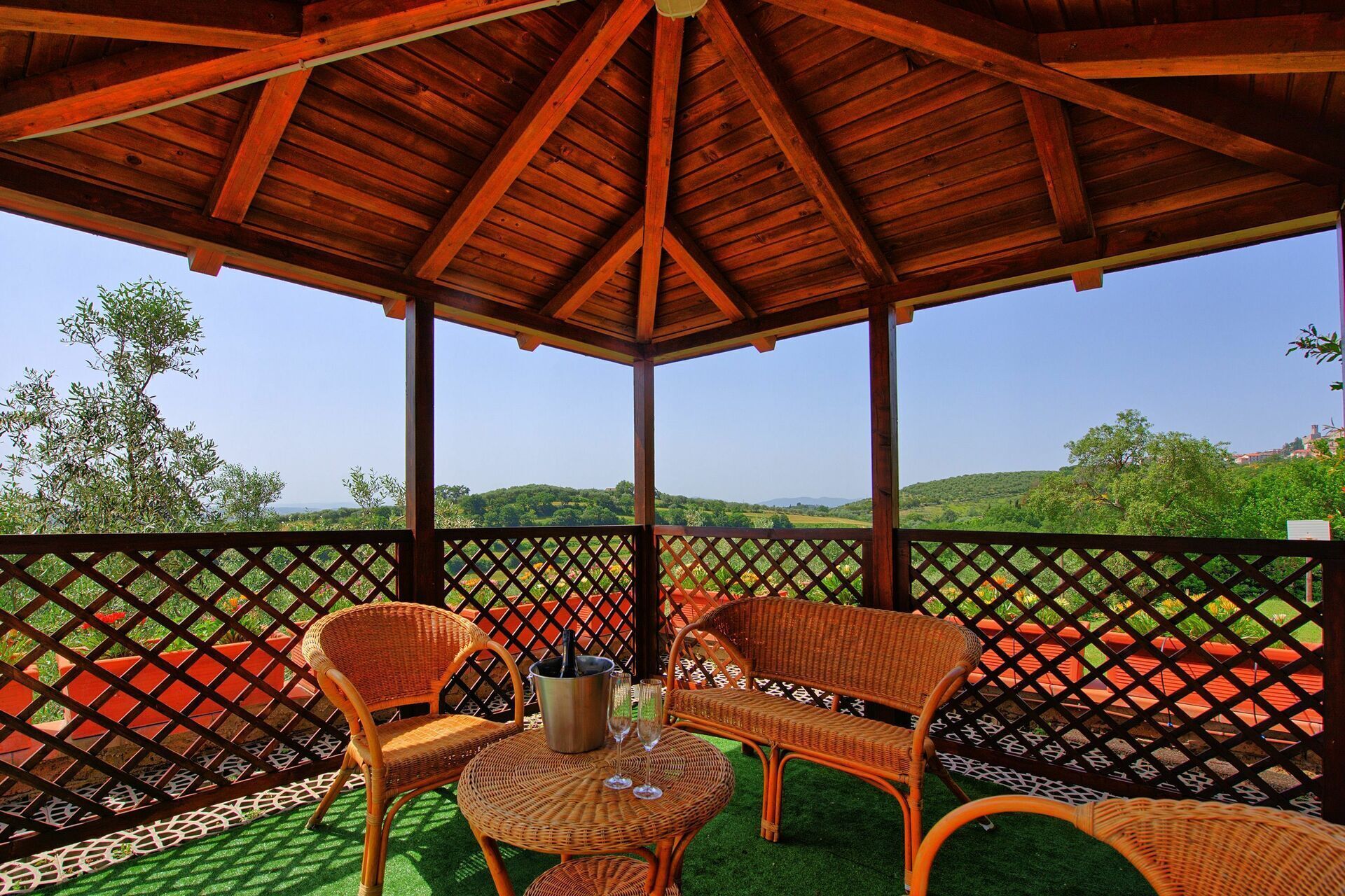 Un espacio de estar techado al aire libre con muebles de mimbre y vistas a colinas verdes.