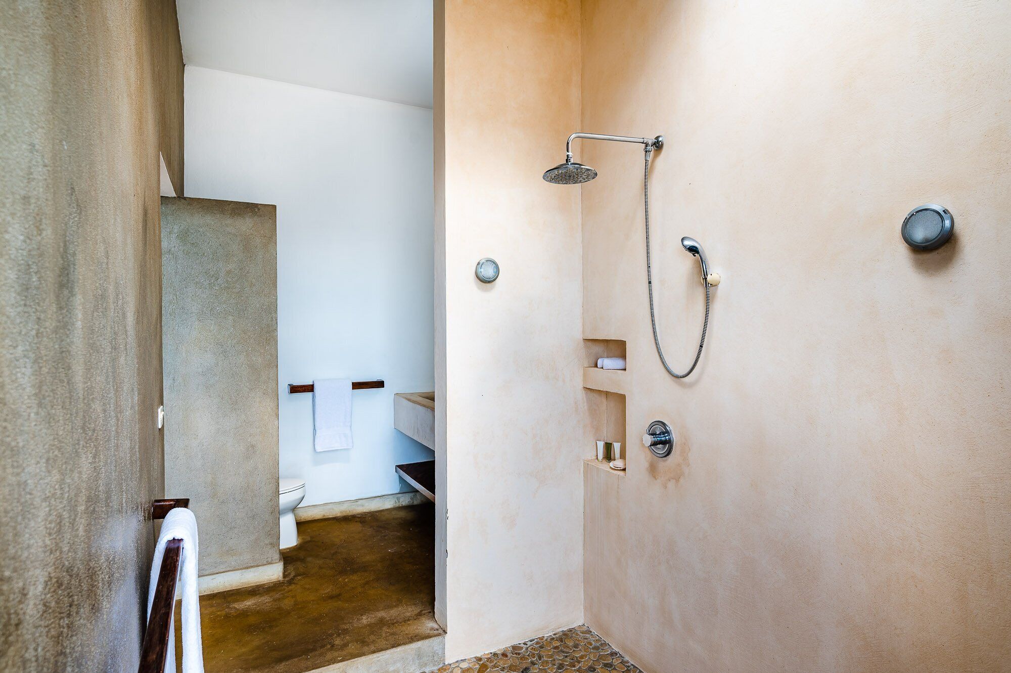 Casa de banho com chuveiro, sanita e um porta-toalhas.