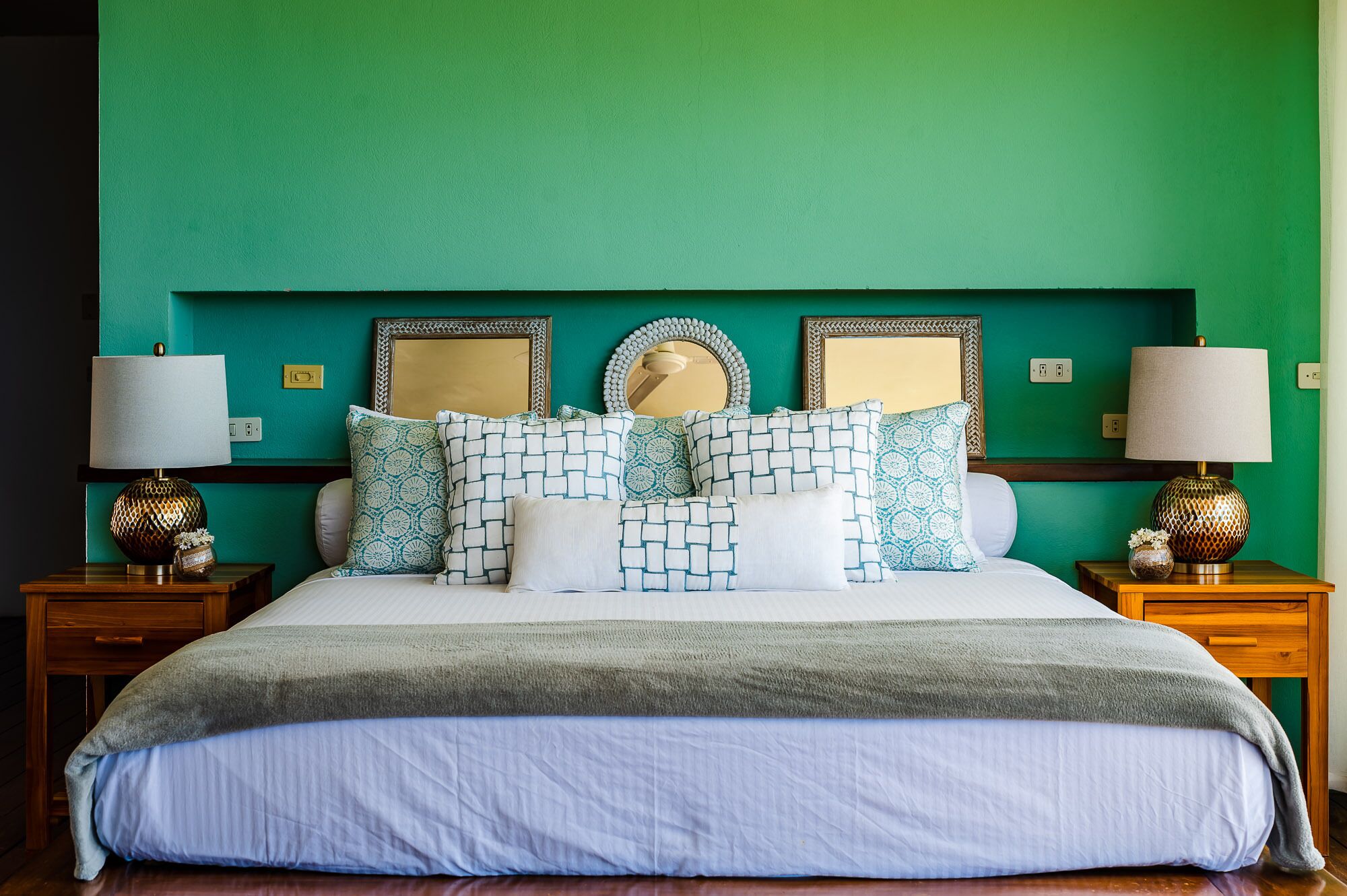 A bed with multiple pillows and a blanket, flanked by two nightstands with lamps and decorative vases.