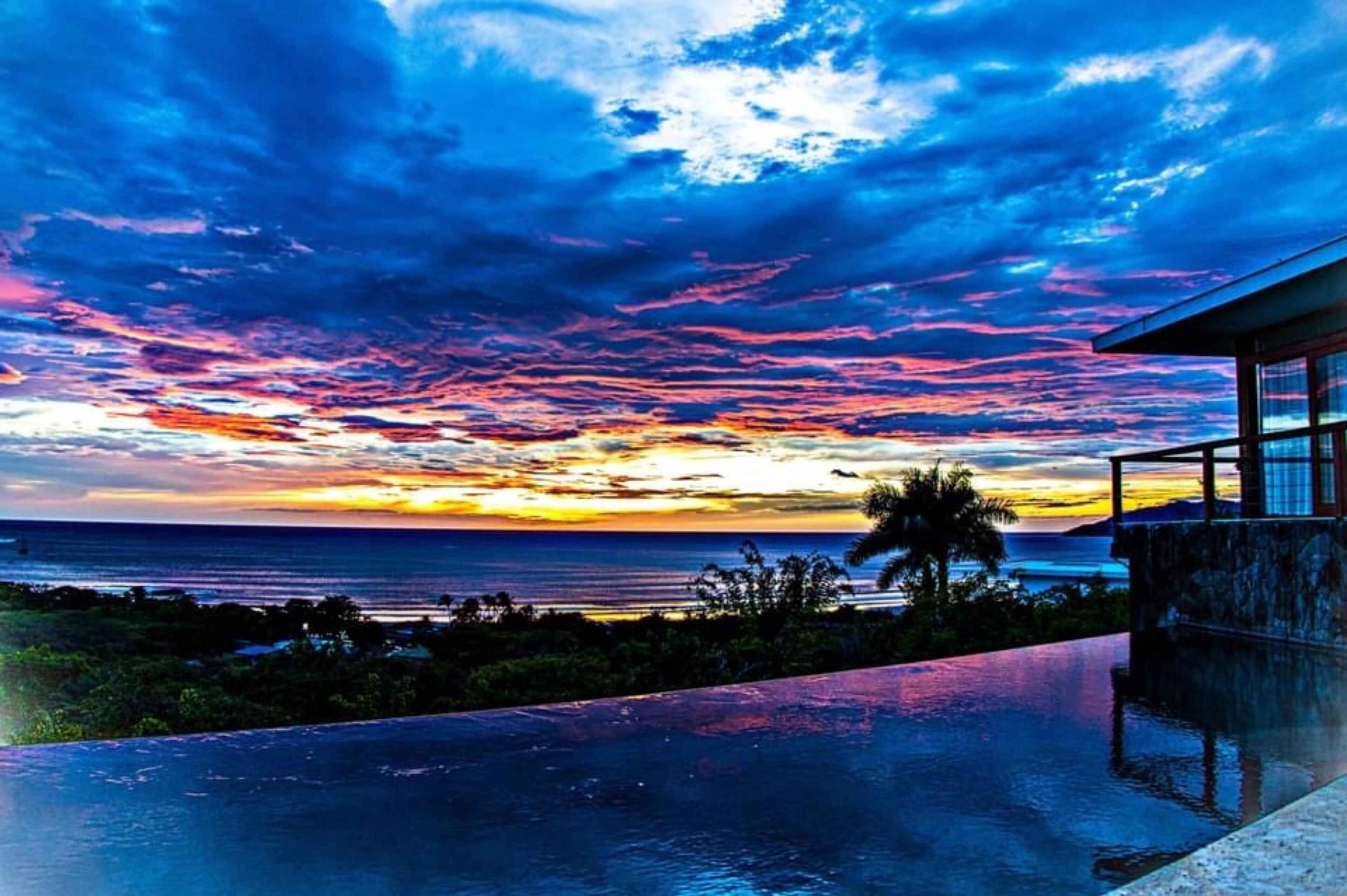 Ein modernes Gebäude mit Pool und Blick auf einen Sonnenuntergang.