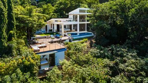 A modern two-story house with a swimming pool, surrounded by lush greenery. - Ocean Views · Infinity Pool · 3 min to the Beach & Exclusive Beach Club Access (Tamarindo)