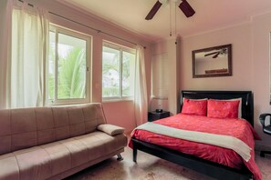 A bedroom with a bed, a sofa, a ceiling fan, and a window with curtains. - Playa Turquesa K301_200Mbps_Private Beach Access_BBQ_Pools (Punta Cana)