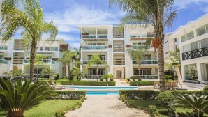 Un hôtel moderne, doté de plusieurs étages, d’une piscine et de jardins bien entretenus.