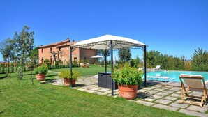 Patio trasero con piscina, un porche cubierto y una casa de ladrillo.