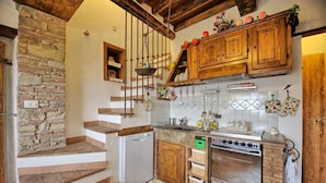 Eine rustikale Küche mit einer Steinwand, einer Holztreppe und einem eingebauten Backofen.