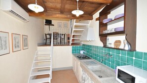 Een keuken met een houten plafond, een gasfornuis, een magnetron en een spoelbak.