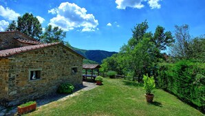 A stone building with a tiled roof, surrounded by a well-maintained lawn and trees. - Villa Margherita Uno - Holiday Villa Rental with swimming pool in Cortona, Tuscany (Cortona)