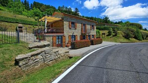 A stone building with a balcony, a paved driveway, and a curved road. - Villa Portole Uno - Holiday Villa Rental in Cortona (Tornia)