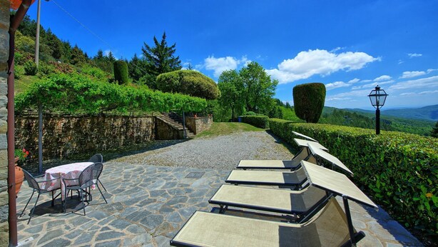 A patio with stone flooring, a table with chairs, and lounge chairs.