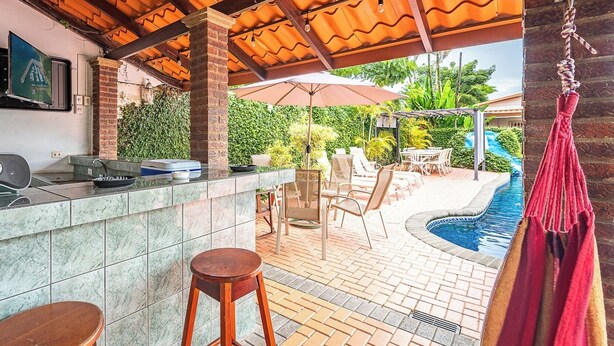 Ein Außenbereich mit Bar, Pool, Liegestühlen und einer Hängematte.