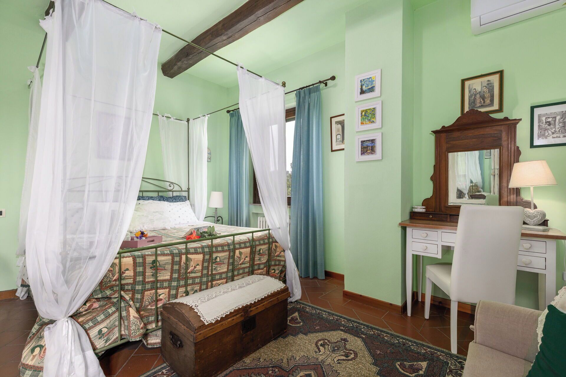 A room with a bed, a desk, a chair, a mirror, and a small chest of drawers.