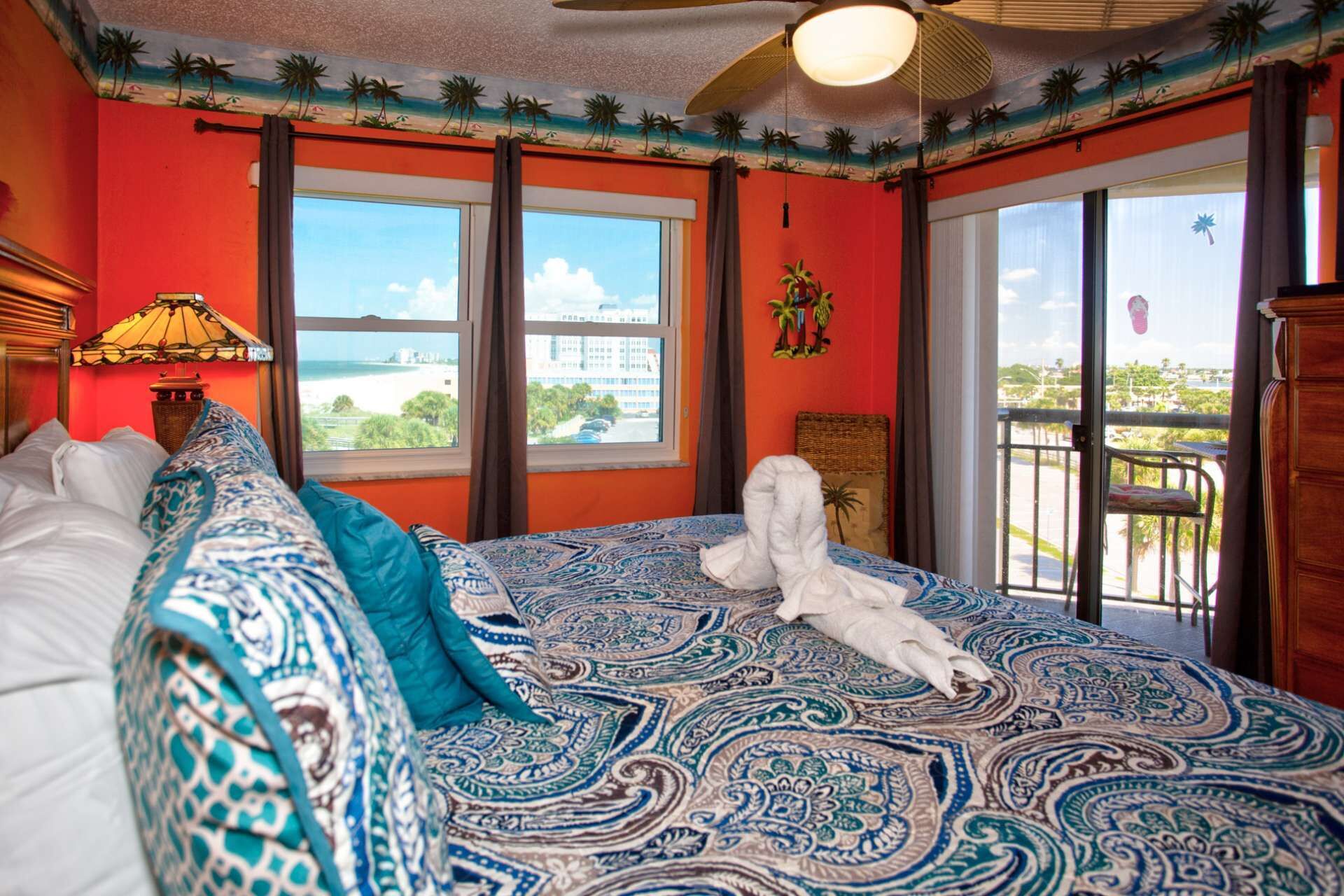 Una habitación con una cama grande, vista a la playa y un balcón con barandilla.