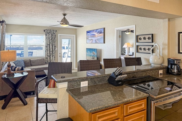 A modern kitchen with a granite countertop, a built-in stove, and a coffee maker.