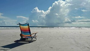 Ein Strand mit einem bunten Liegestuhl und freiem Blick auf das Meer.