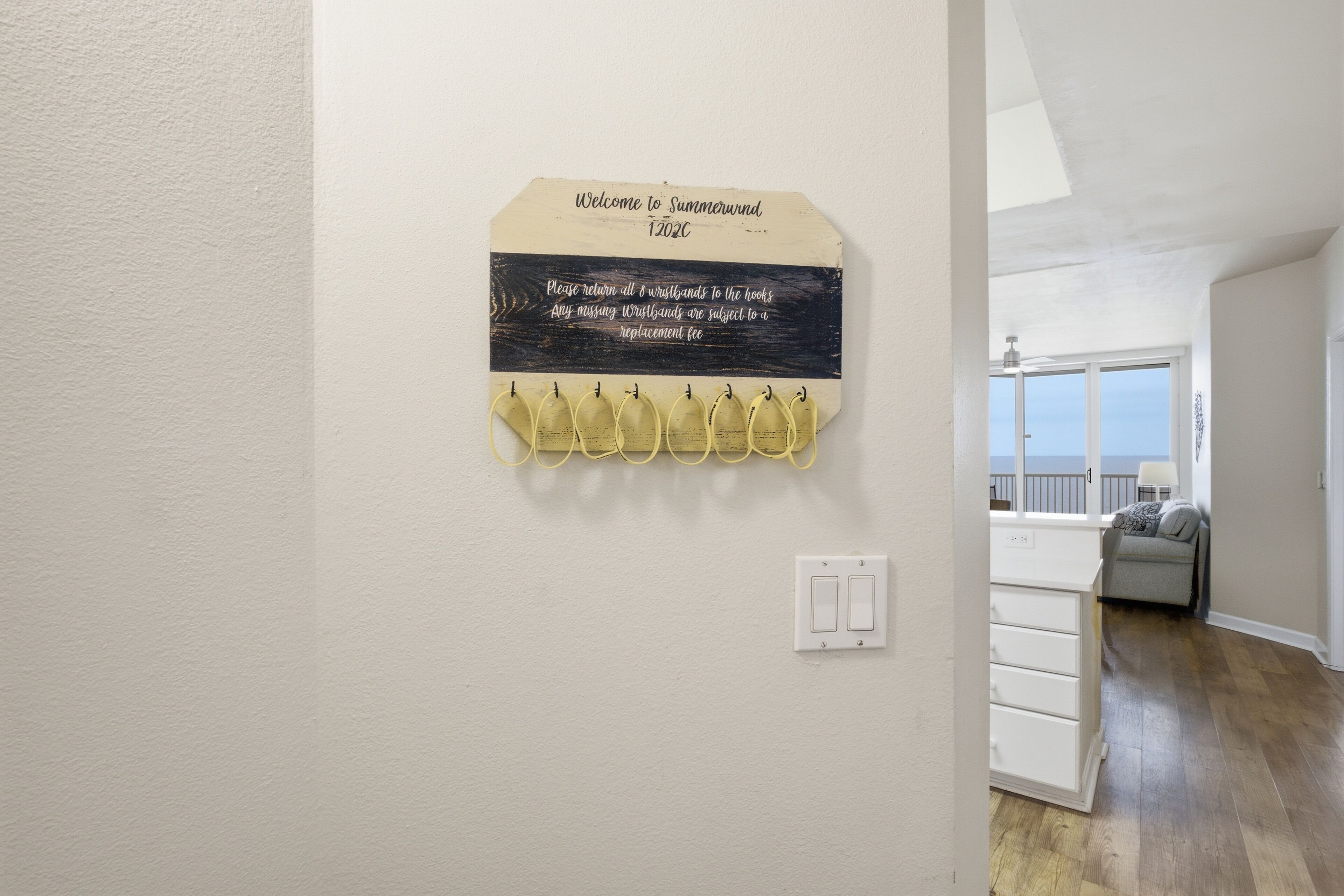 A hallway with a sign on the wall, a coat rack, and a light switch.