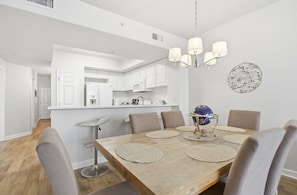 Un comedor moderno con una mesa de madera, sillas tapizadas en gris, una araña y un elemento decorativo en la pared.