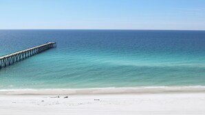 Ein Strand mit einem Steg, der ins Meer führt.