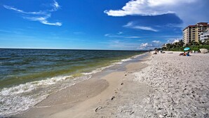 A beach with a clear sky, calm sea, and buildings in the background. - Superb Naples Home w/ Den & Private Saltwater Pool (Naples)